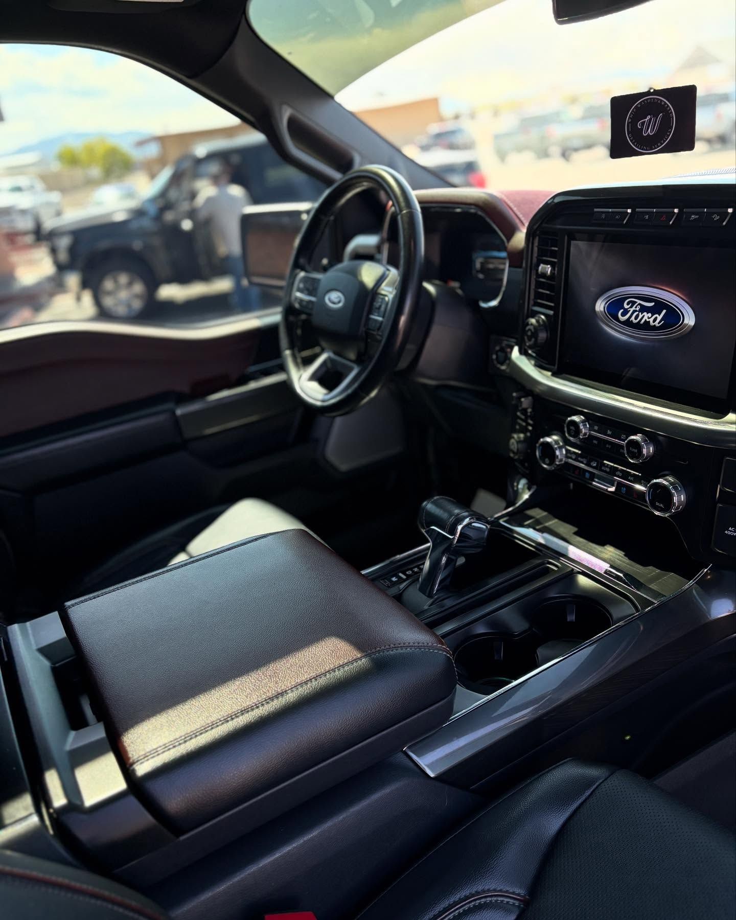 The interior of a modern Ford truck with a dark leather dashboard, steering wheel, and center console.