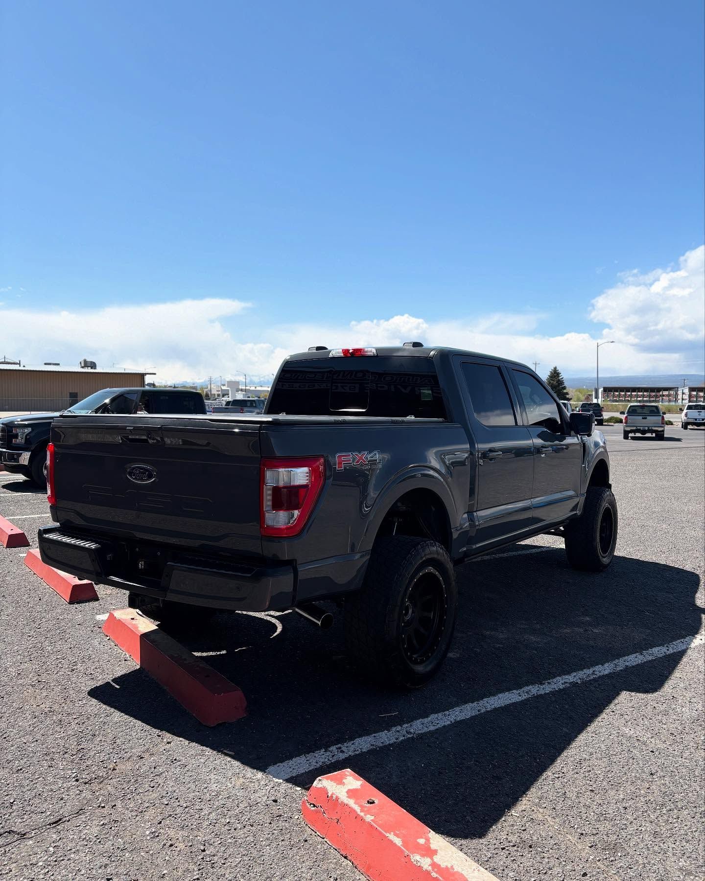 A dark grey pickup truck parked in an outdoor lot on a sunny day.