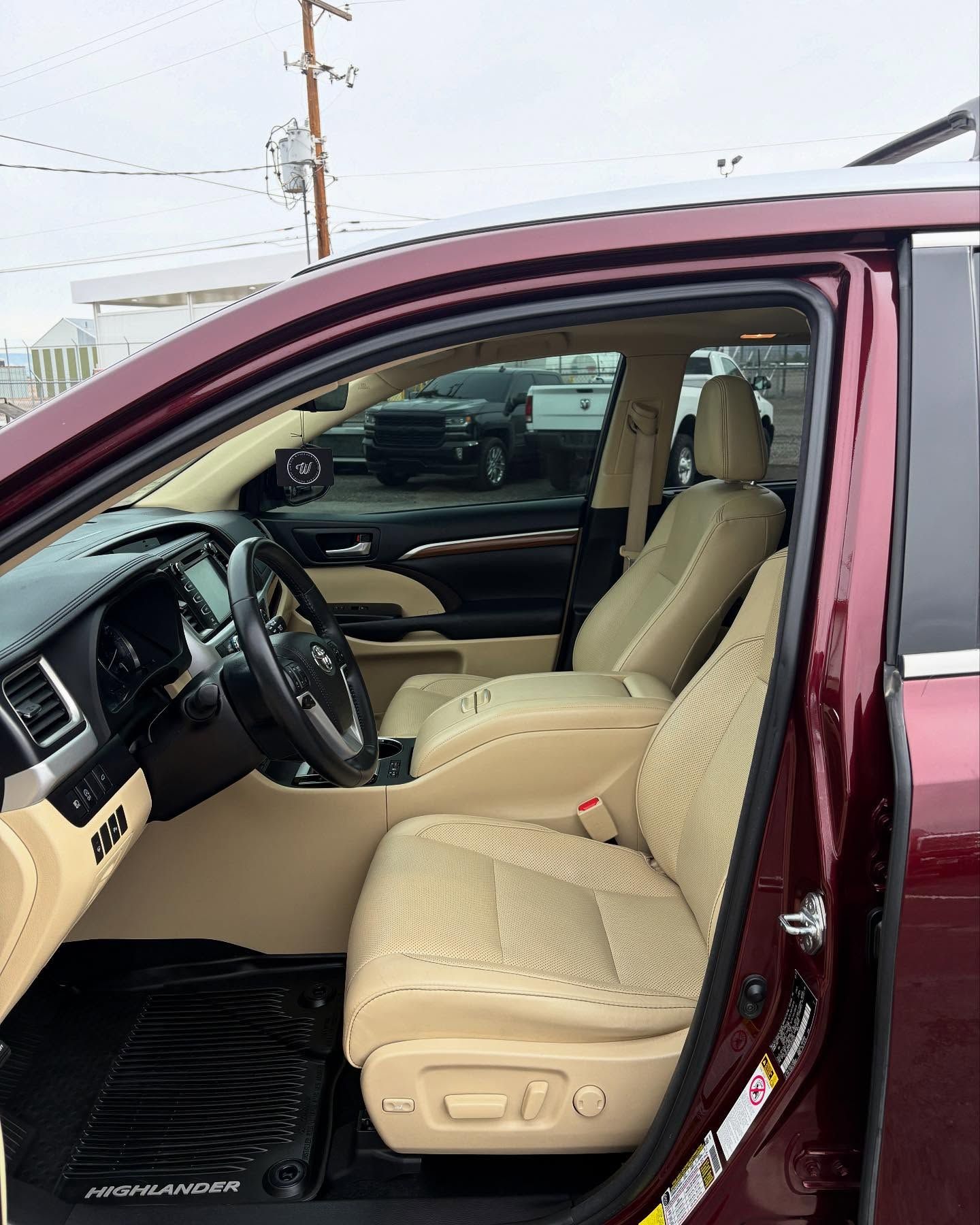 The interior of a maroon vehicle featuring tan leather bucket seats, a black dashboard, and a steering wheel.