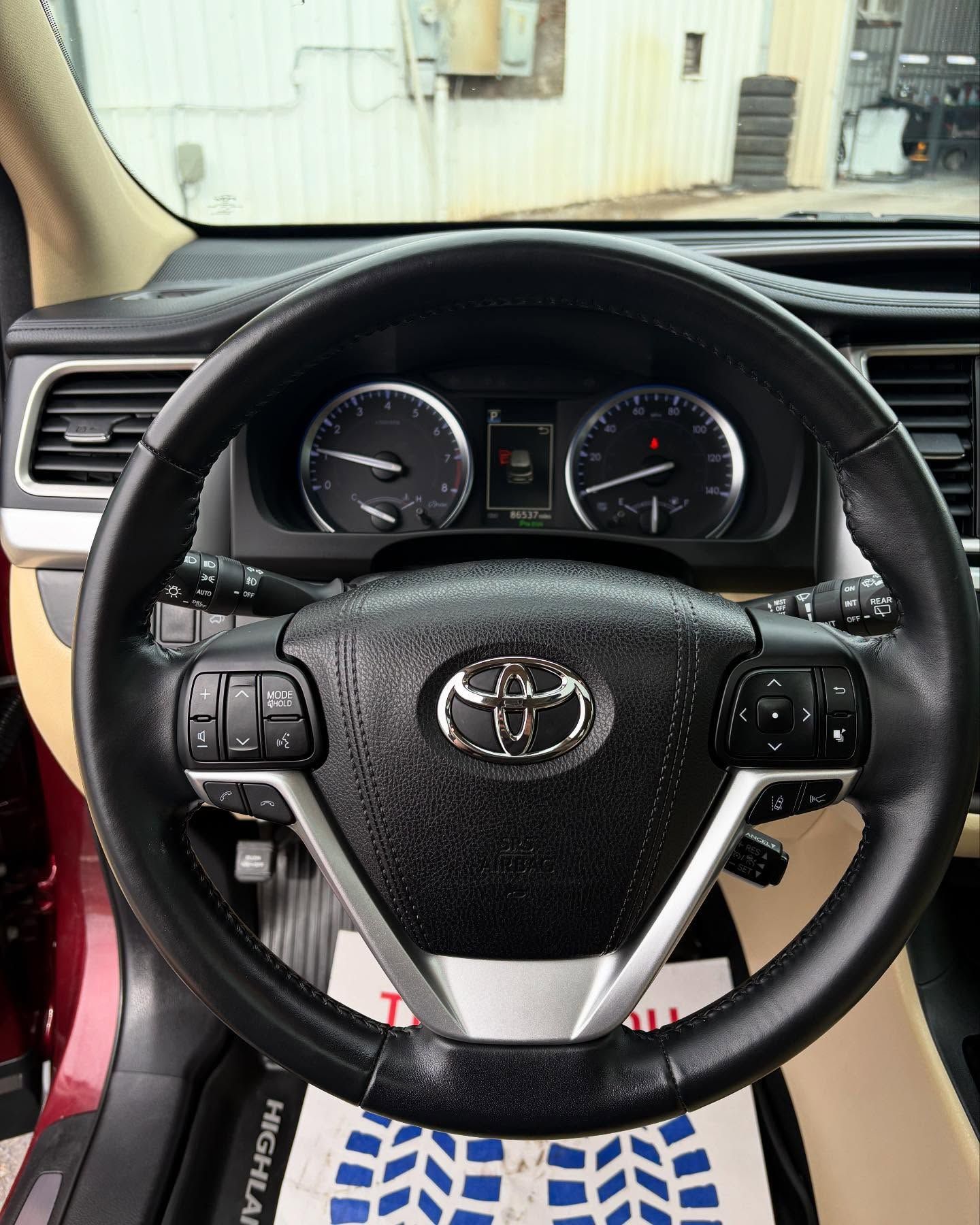 The driver's perspective from inside a car, showing the black Toyota steering wheel, dashboard, and instrument cluster.