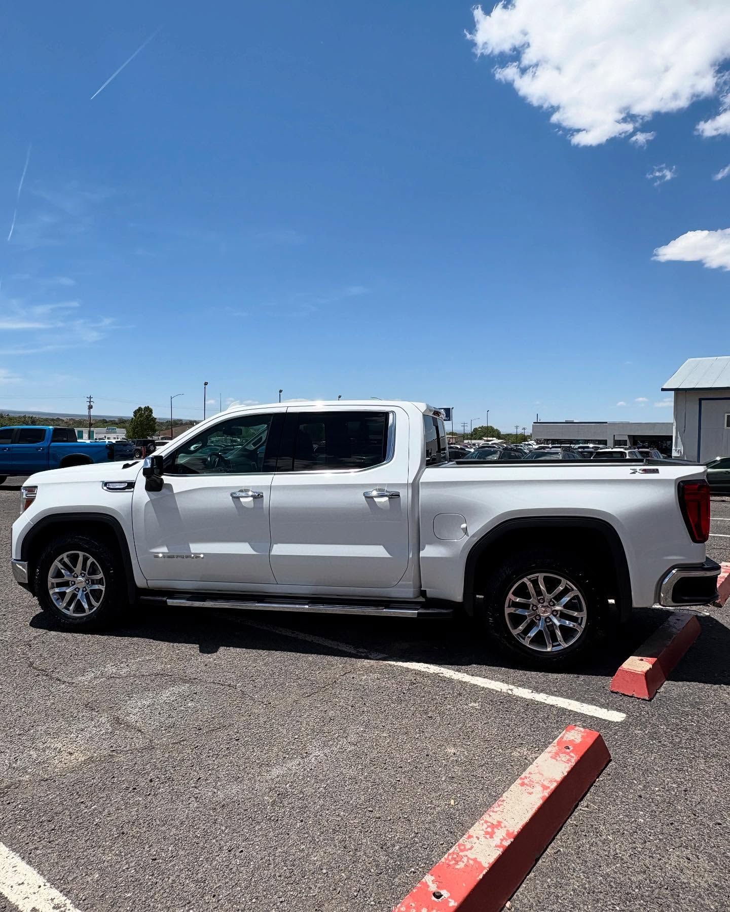 A white pickup truck parked in an outdoor lot under a clear blue sky.