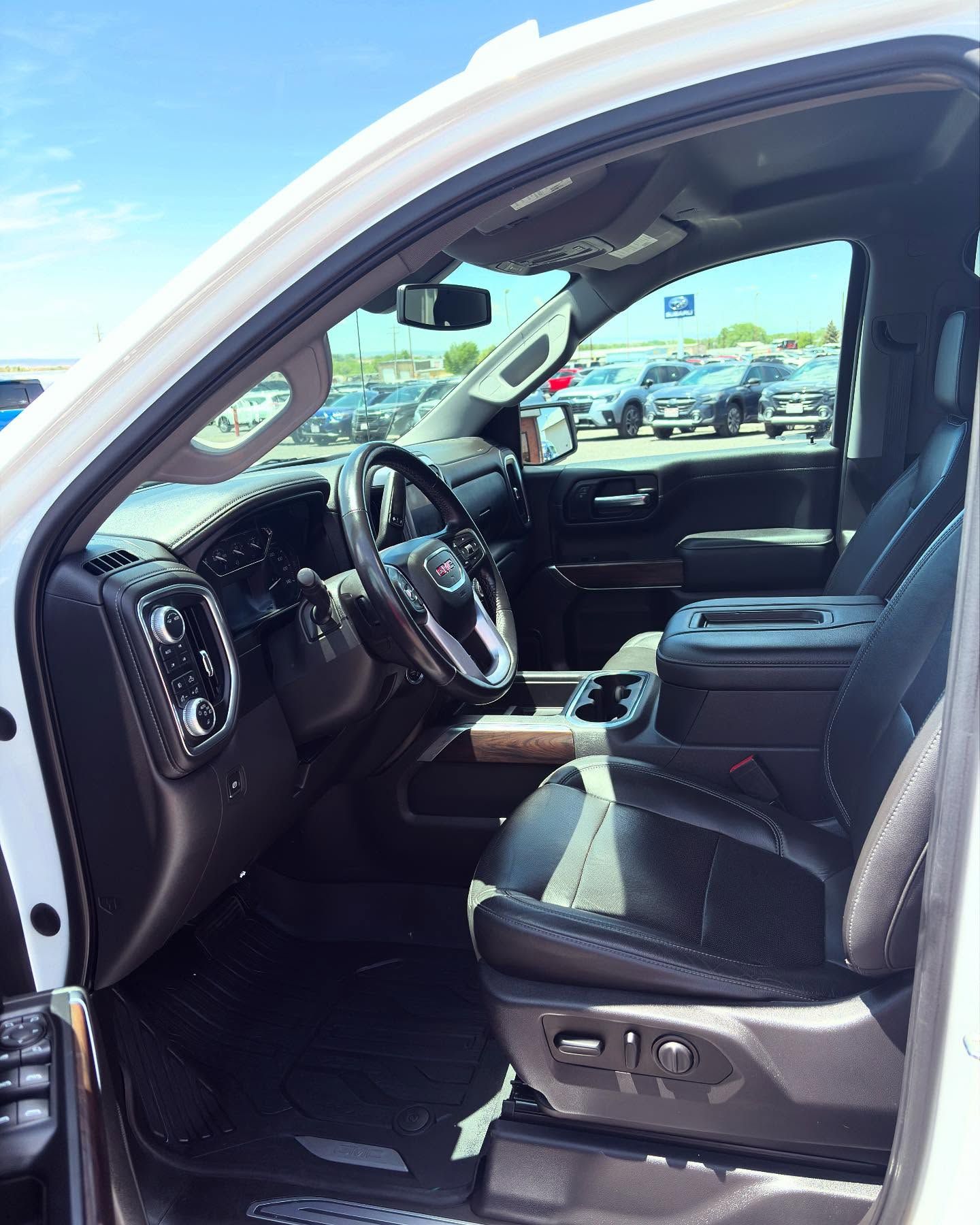 Interior view of a pickup truck with black leather seats, a steering wheel, and a center console on a sunny day.