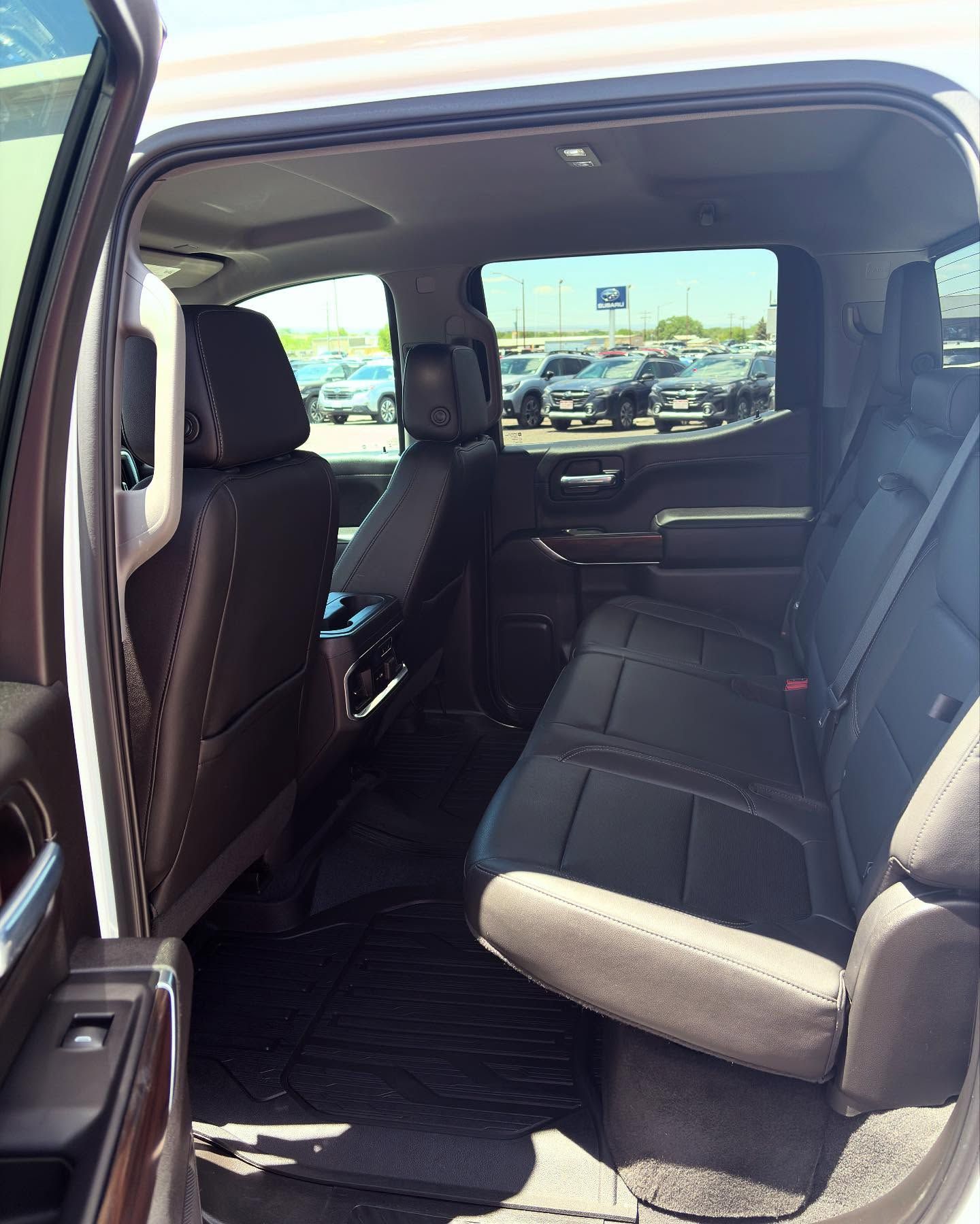 The interior back seat area of a dark-colored pickup truck with leather upholstery, visible through an open door.