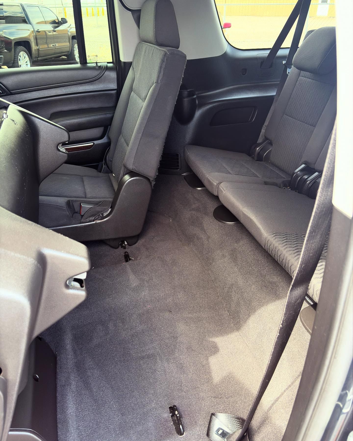 Interior view of a vehicle showing dark gray fabric captain's chairs and a third-row bench seat with carpeted flooring.