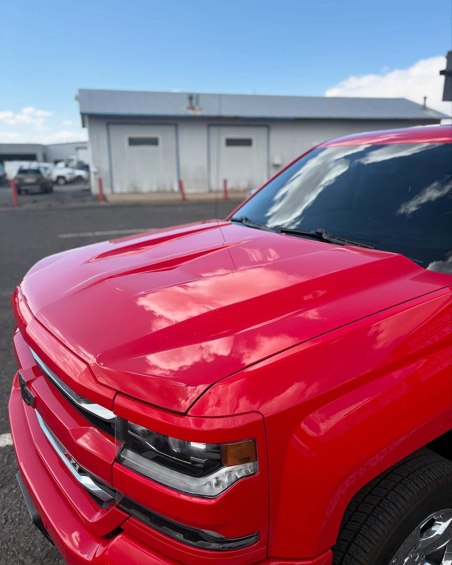 A shiny red pickup truck parked in an outdoor lot on a sunny day.