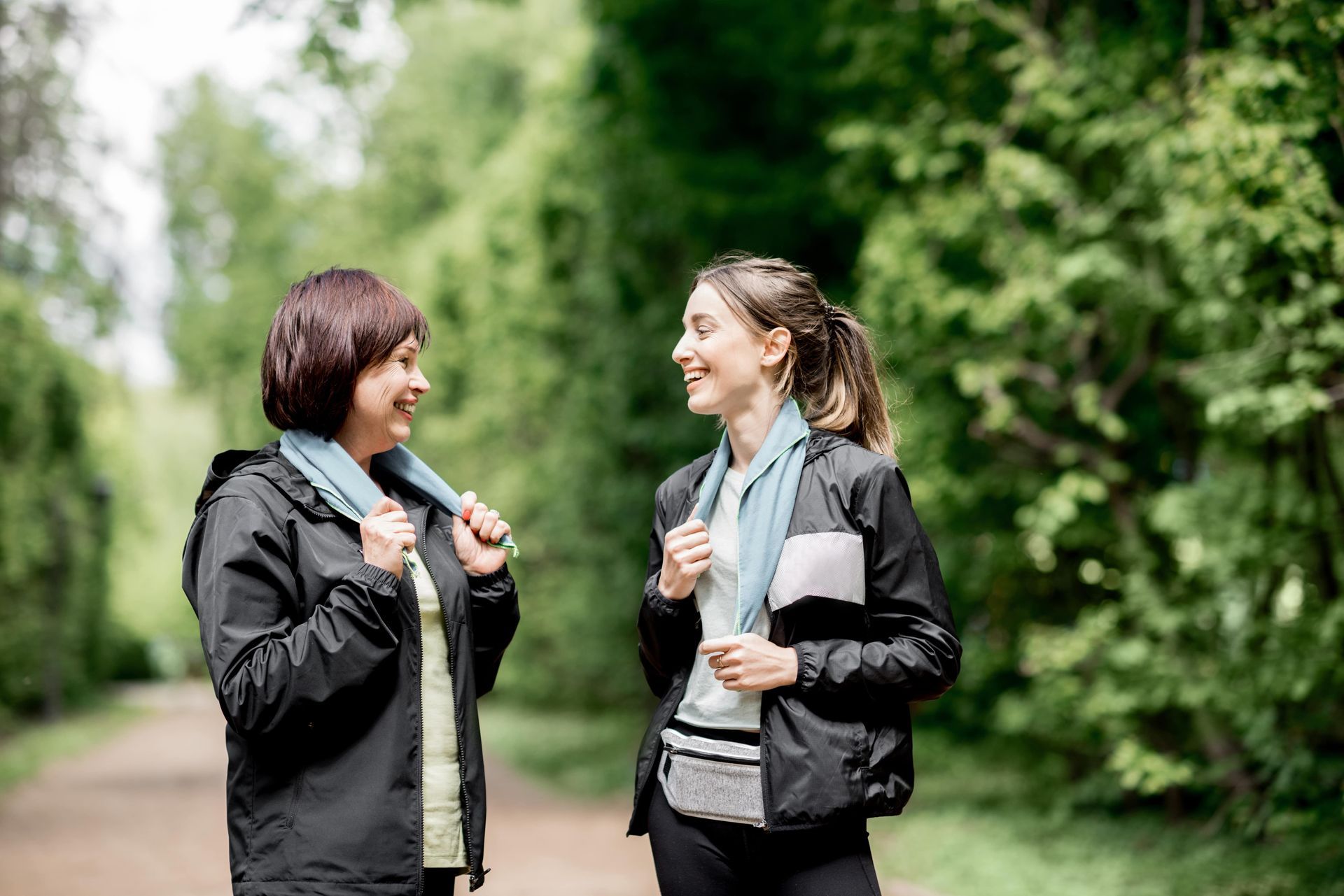 Two women walking on a trail outside.