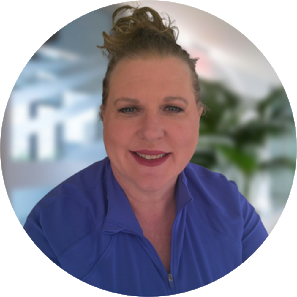 A woman in a green sweater is standing next to a tree.