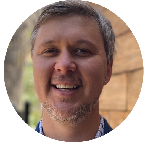 A woman in a green sweater is standing next to a tree.