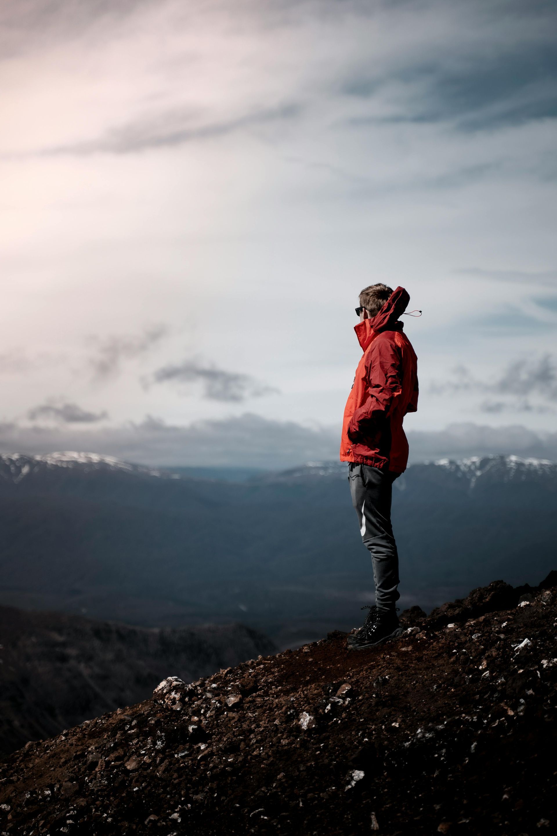 A man staring out at a mountain landscape while standing on one.