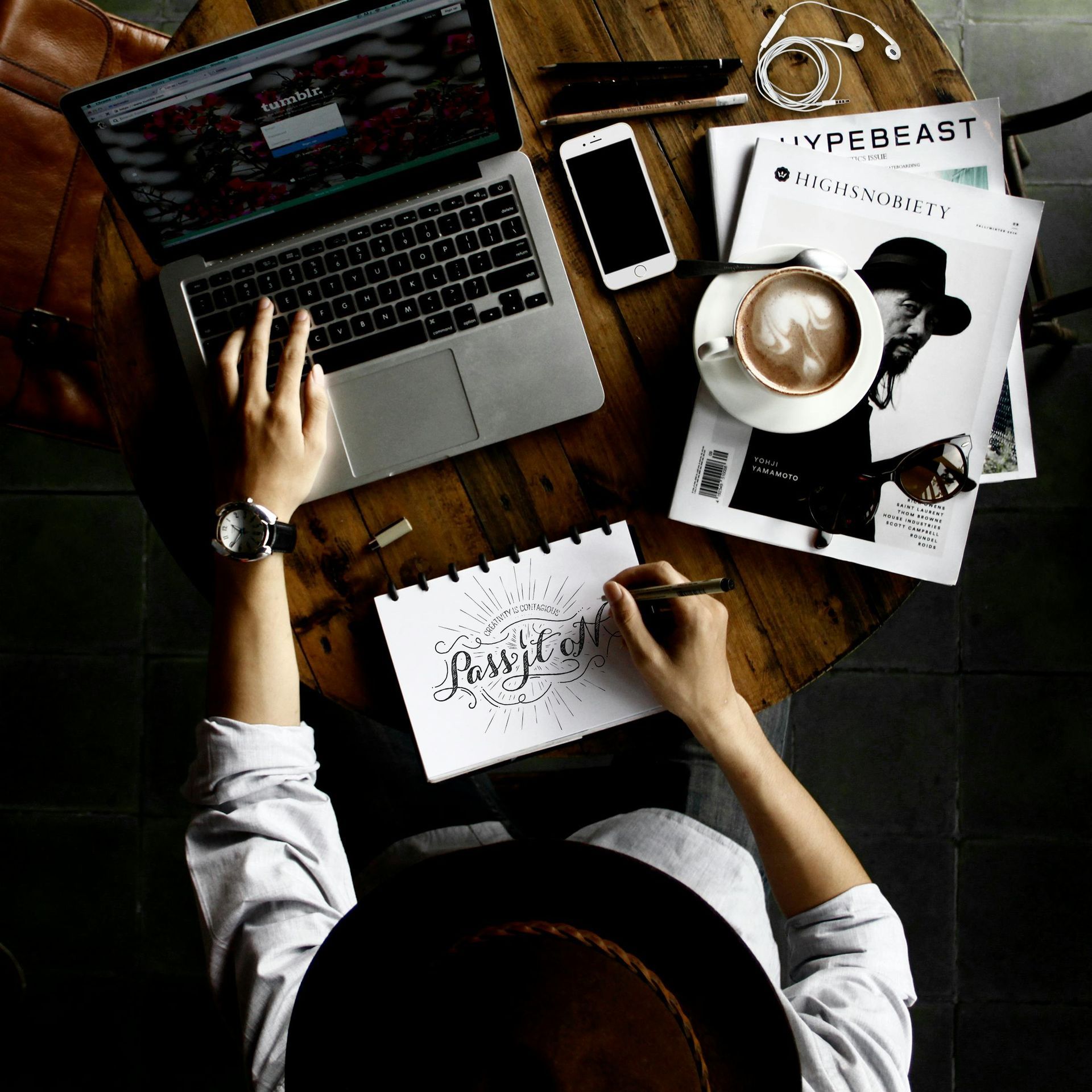 A woman sitting at a computer with coffee and a notebook