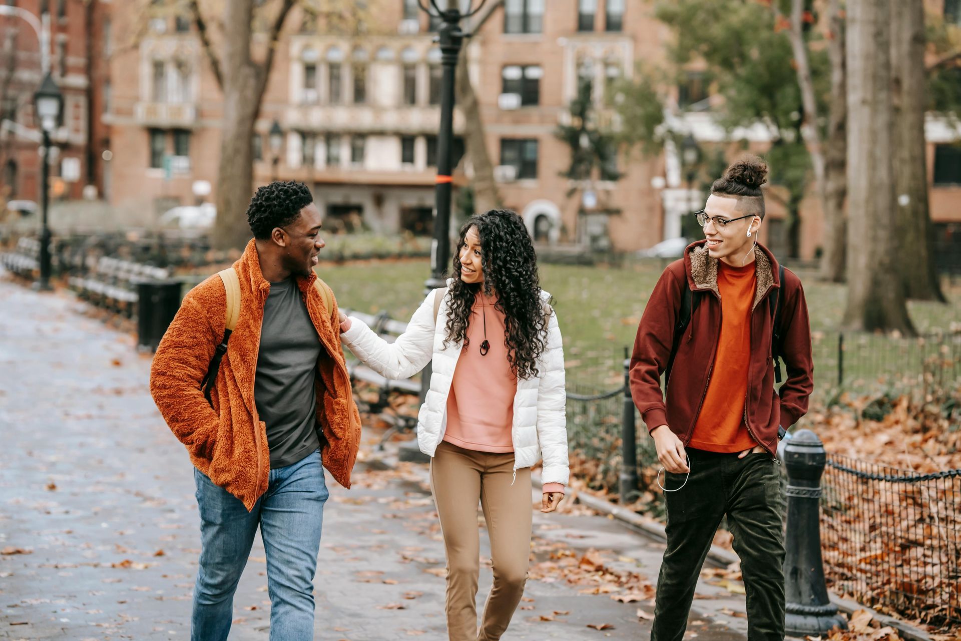 Three young college aged students walking together in the fall