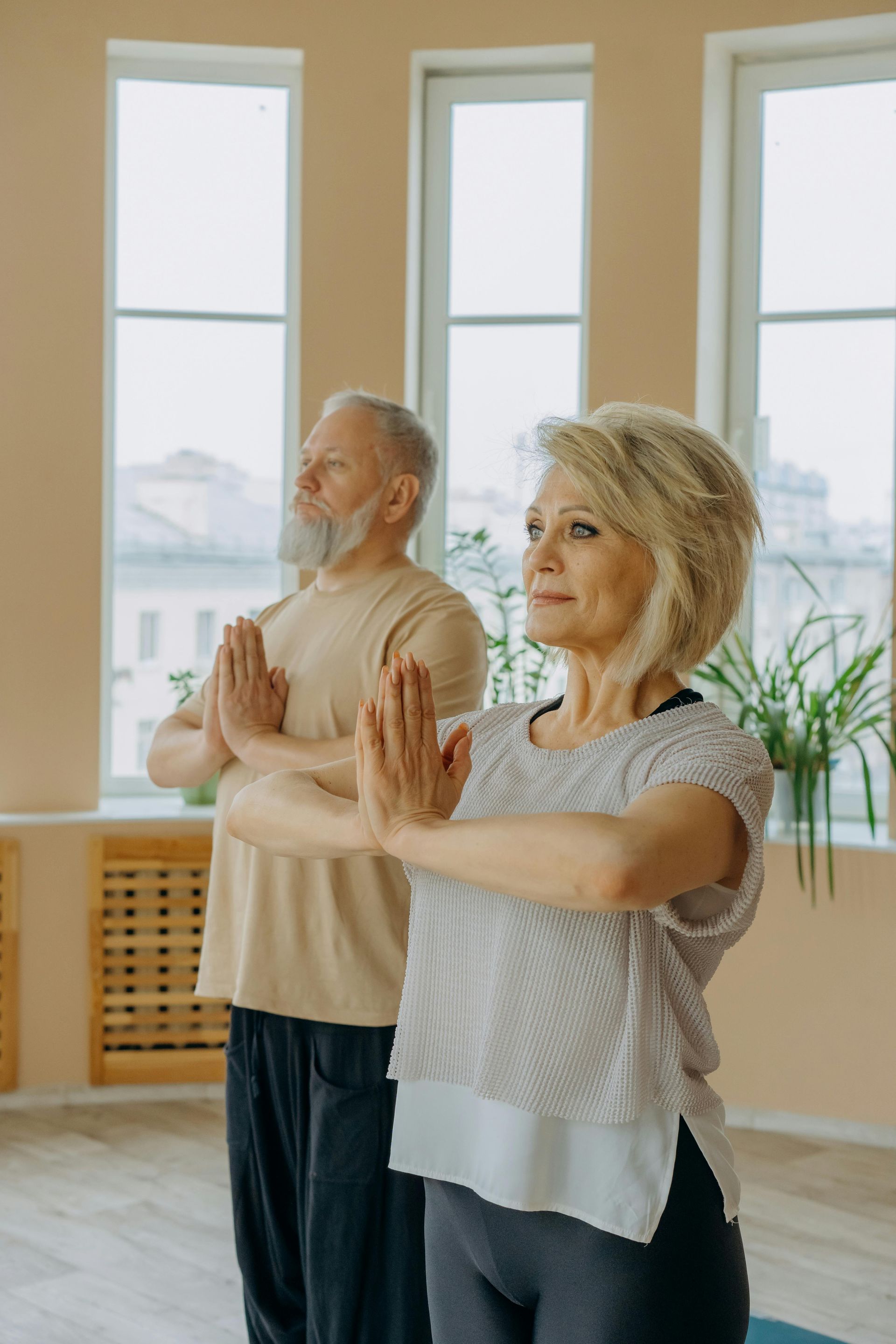 Two older adults, a man and women, doing yoga and looking ahead