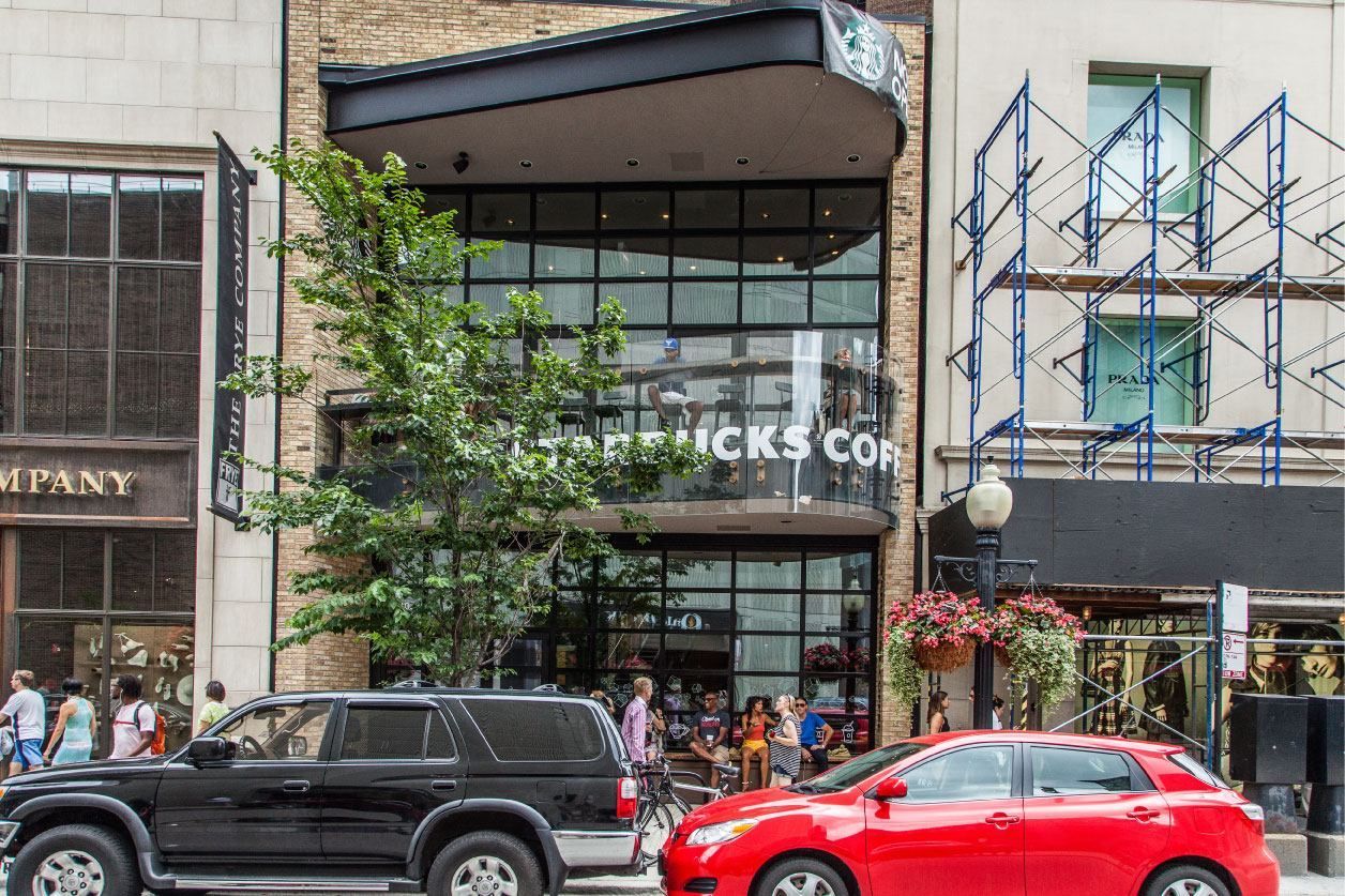 A red car is parked in front of a starbucks coffee shop