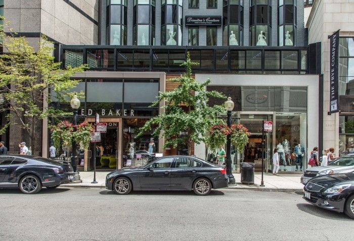 A row of cars are parked in front of a building.