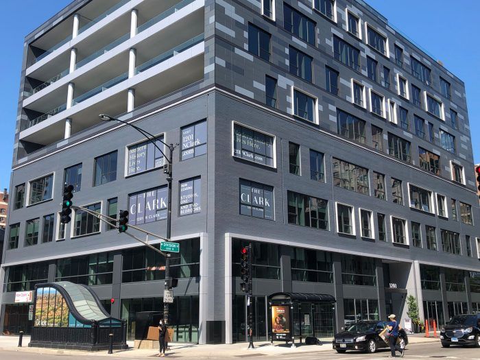 A large building with a lot of windows is on the corner of a city street.
