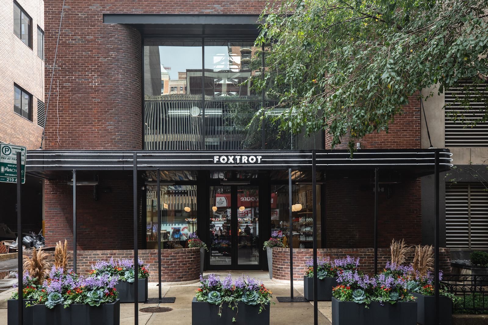 The front of a brick building with flowers in front of it.