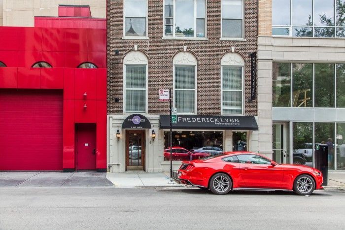 A red car is parked in front of a building.