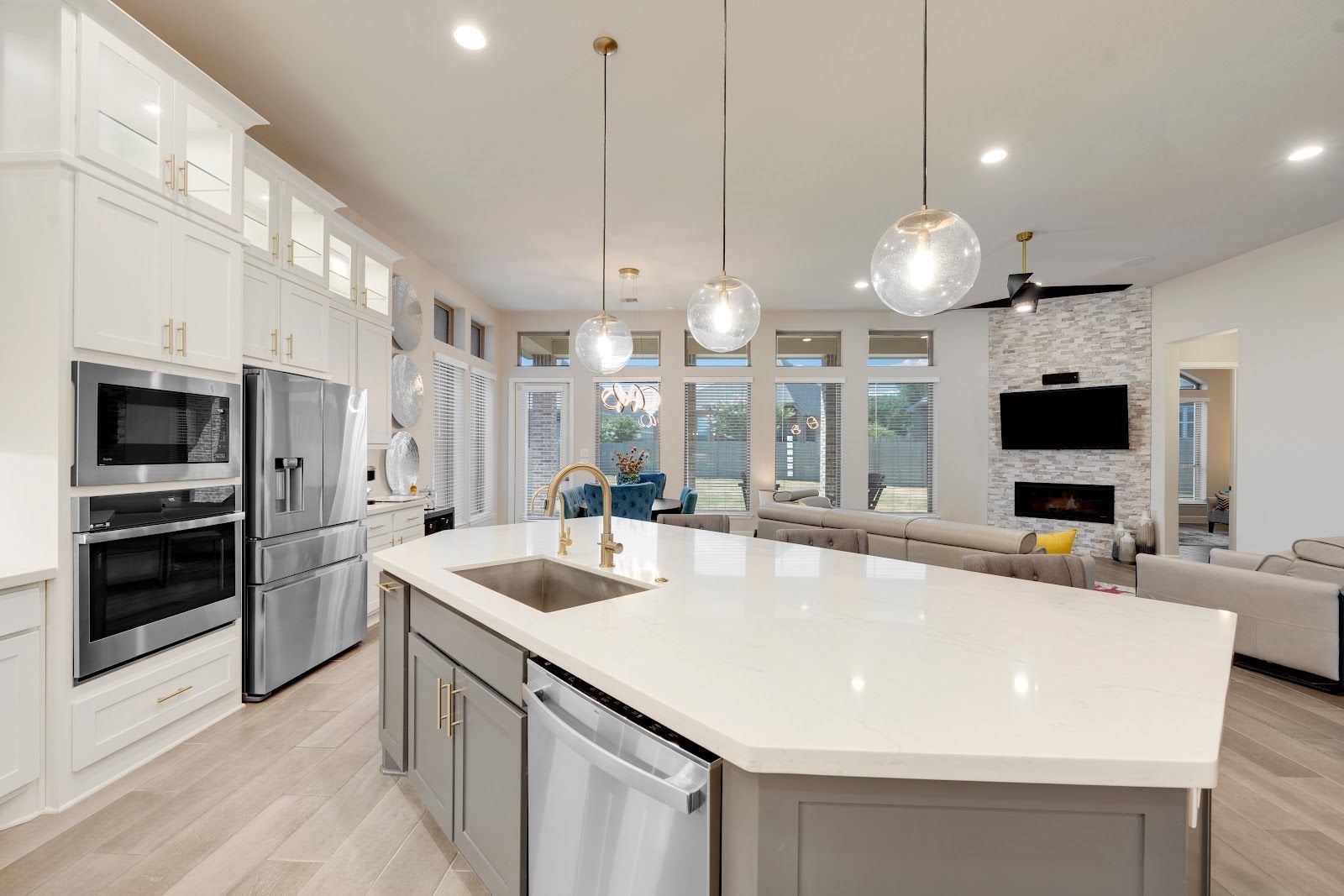 Modern kitchen with white cabinets, gray island, stainless steel appliances, and view of living room.