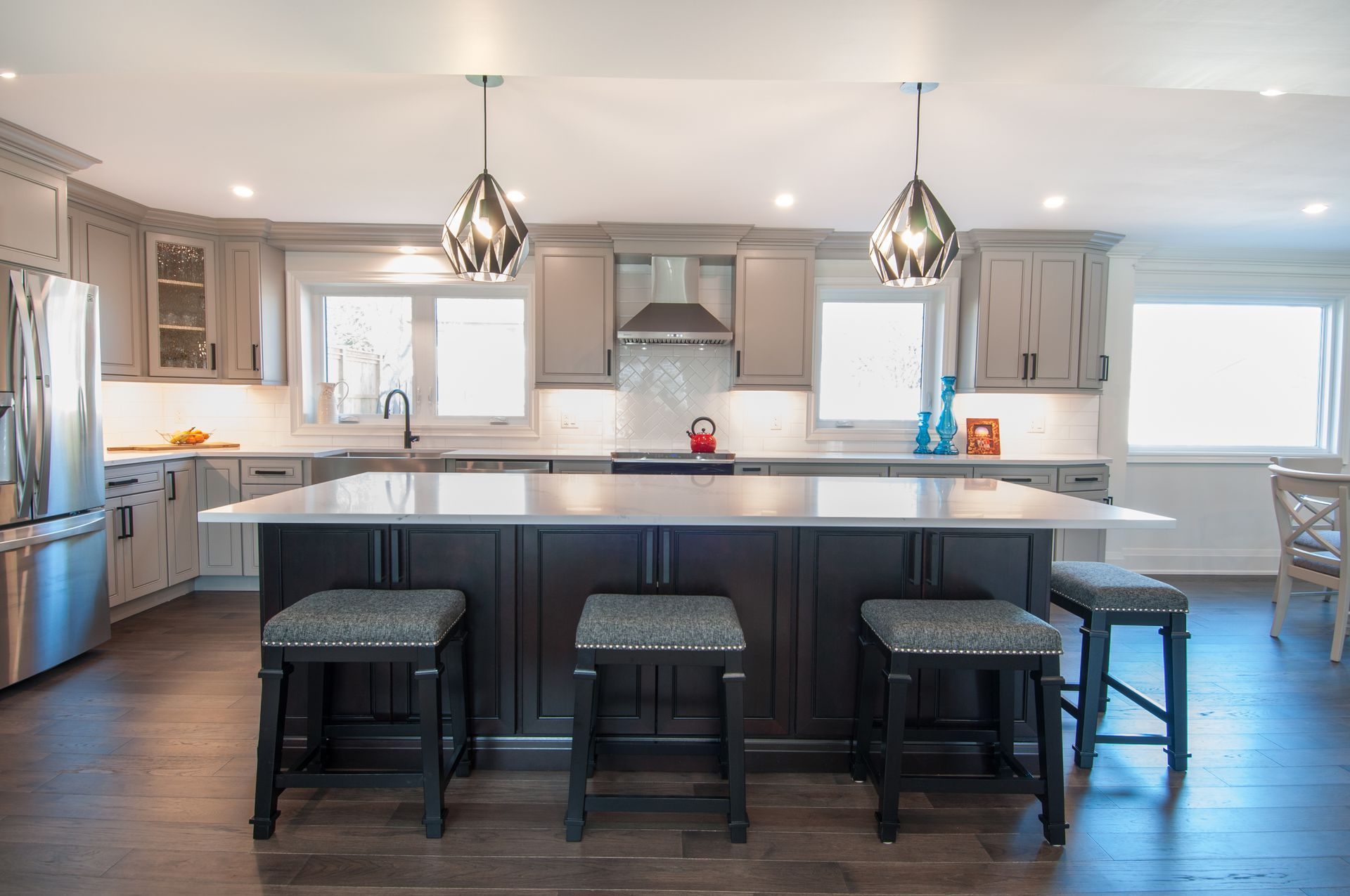 A kitchen with stools and a large island in the middle.