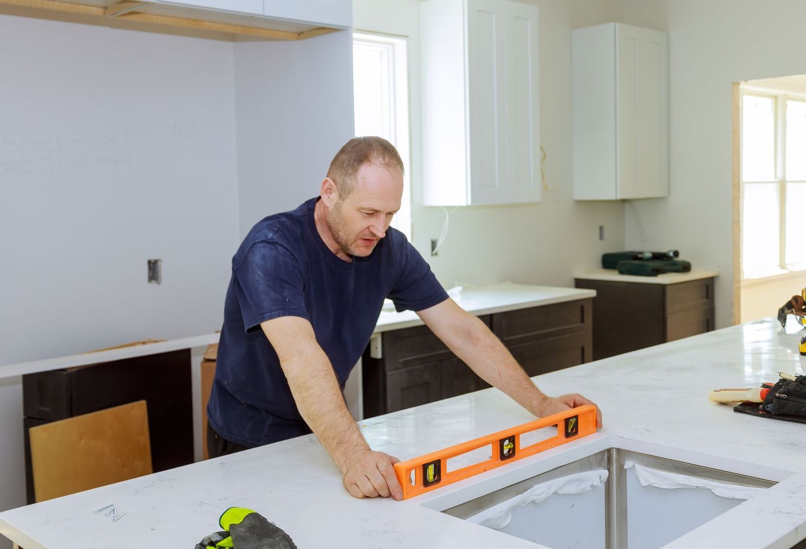 A man is using a level to check the level of a counter top.