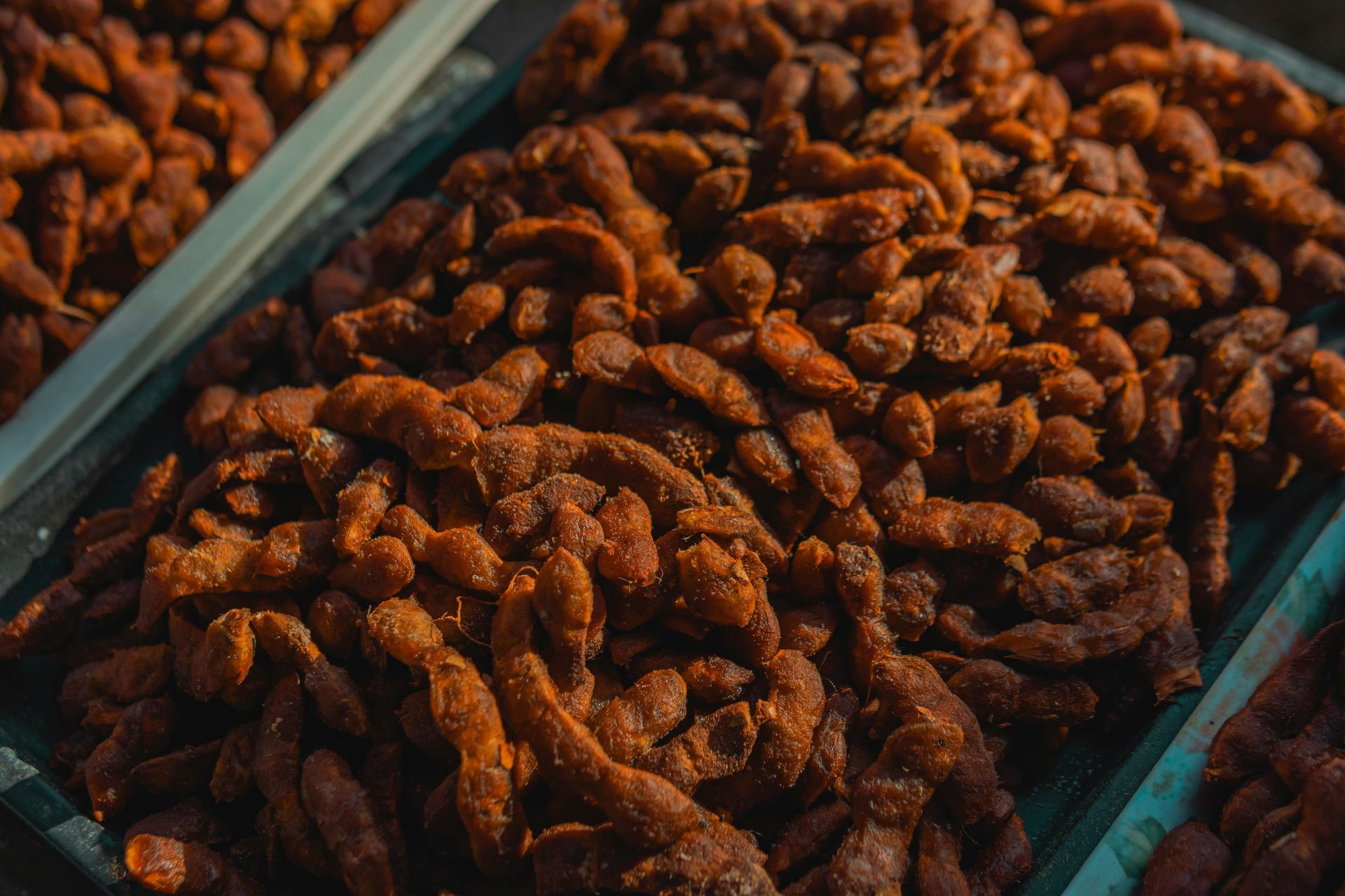 Close-up of a tray filled with many twisted, brown tamarind candies.