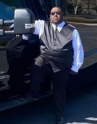 A man is standing in front of a black bus.