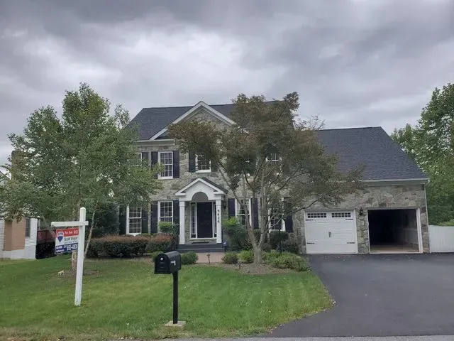 A large house with a for sale sign in front of it