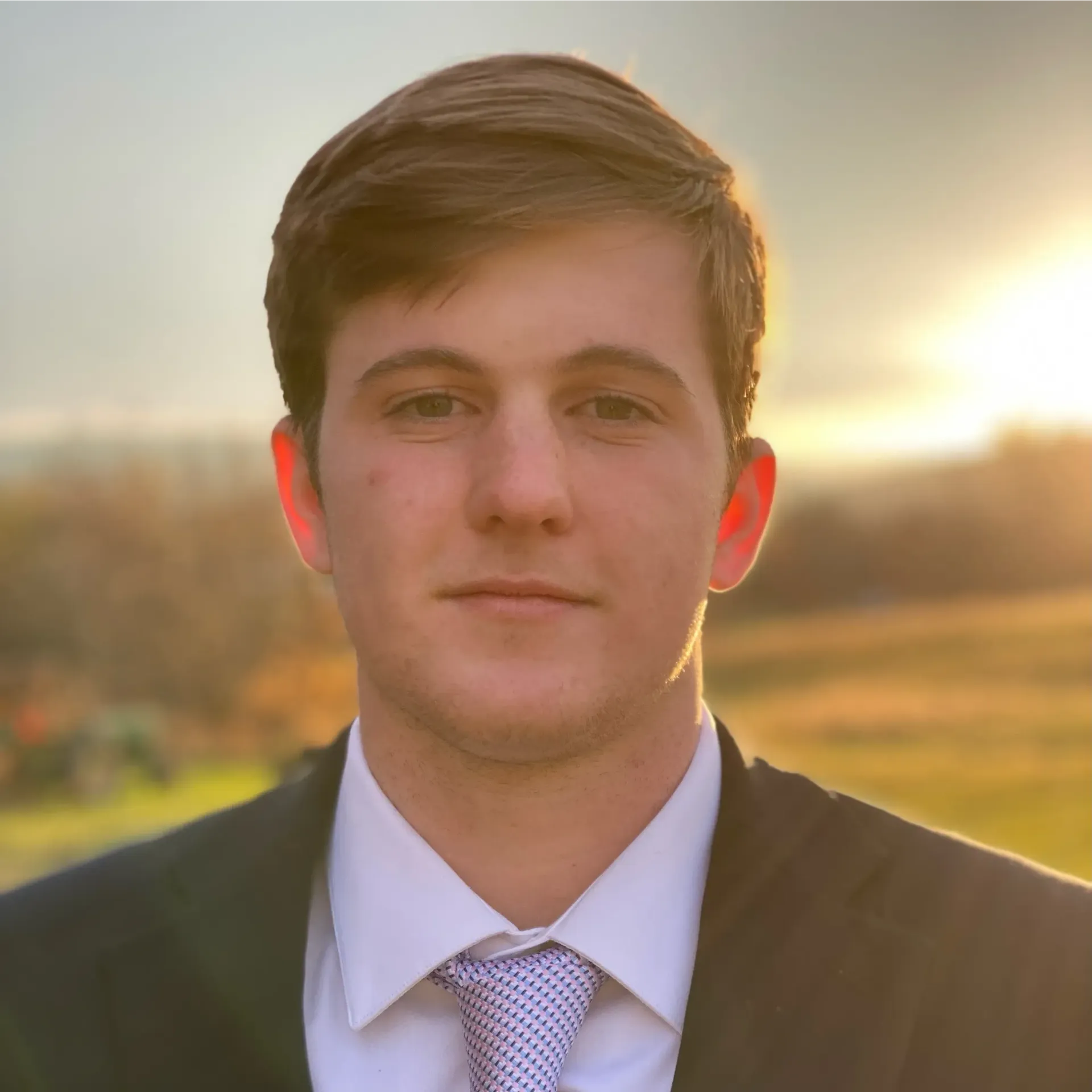 A young man in a suit and tie is looking at the camera.