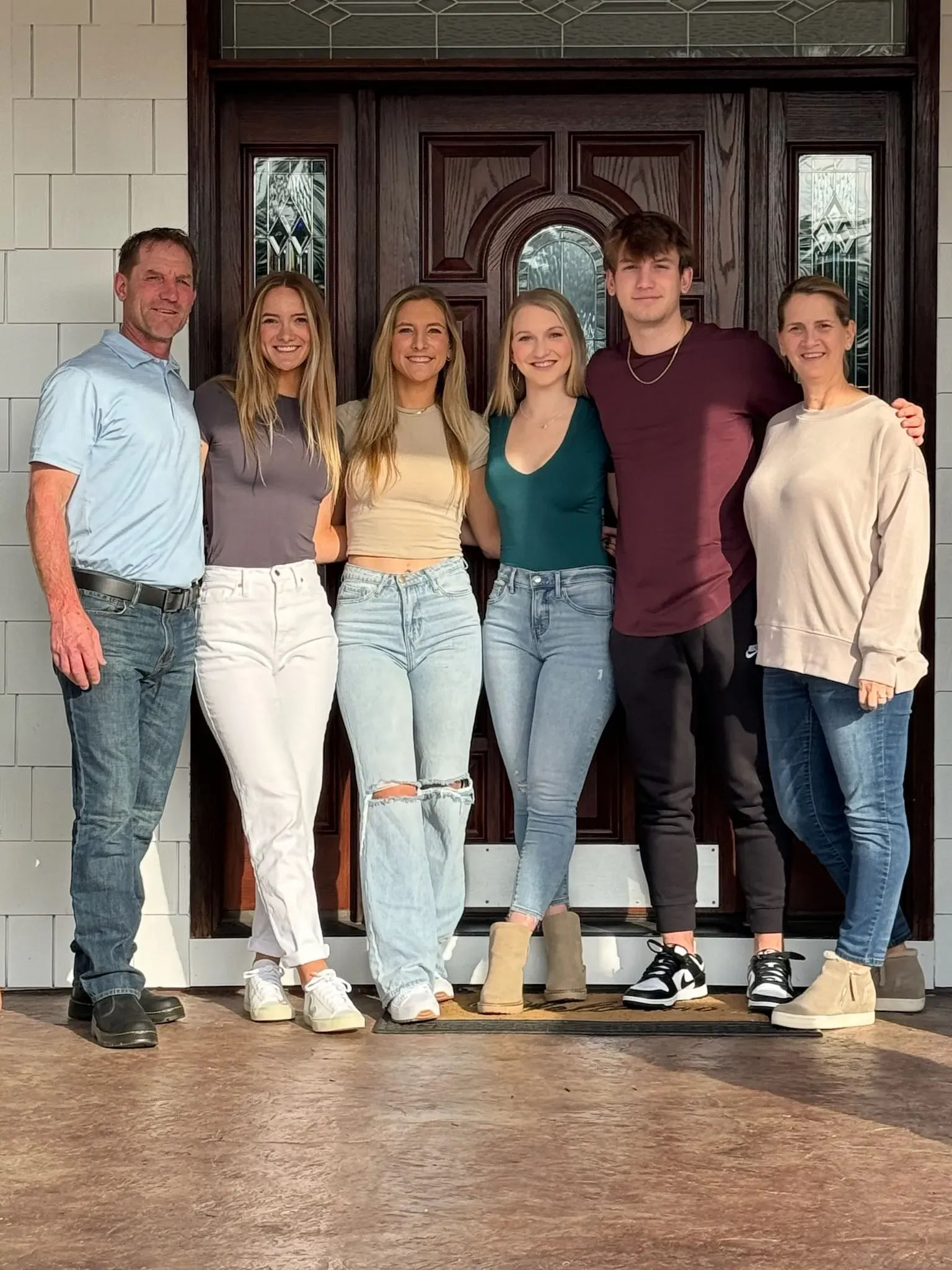 A family is posing for a picture in front of a door.