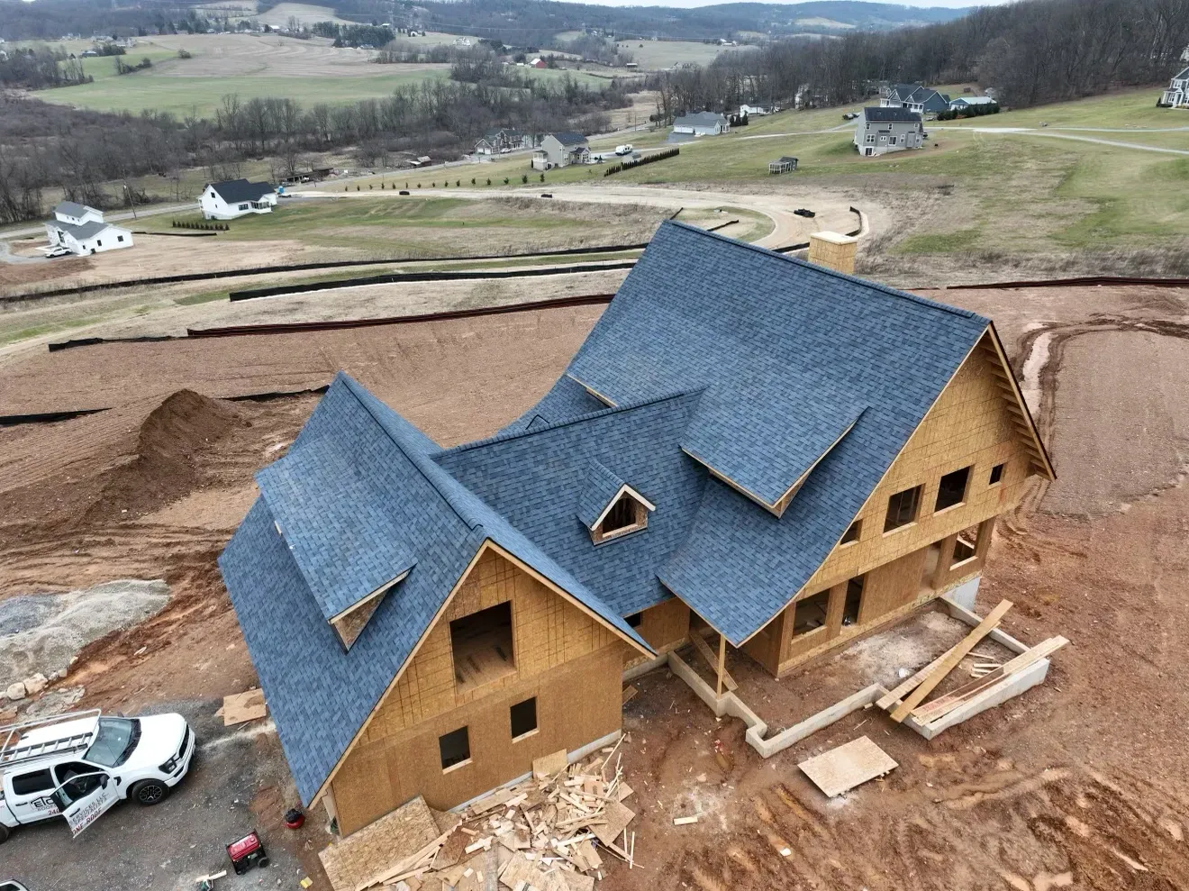 An aerial view of a house under construction with a blue roof.