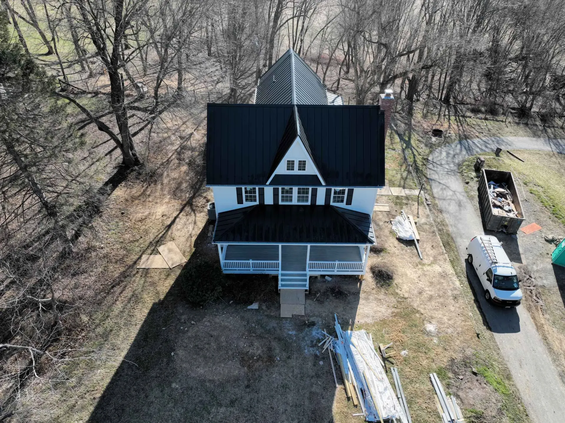 An aerial view of a house with a black roof surrounded by trees.