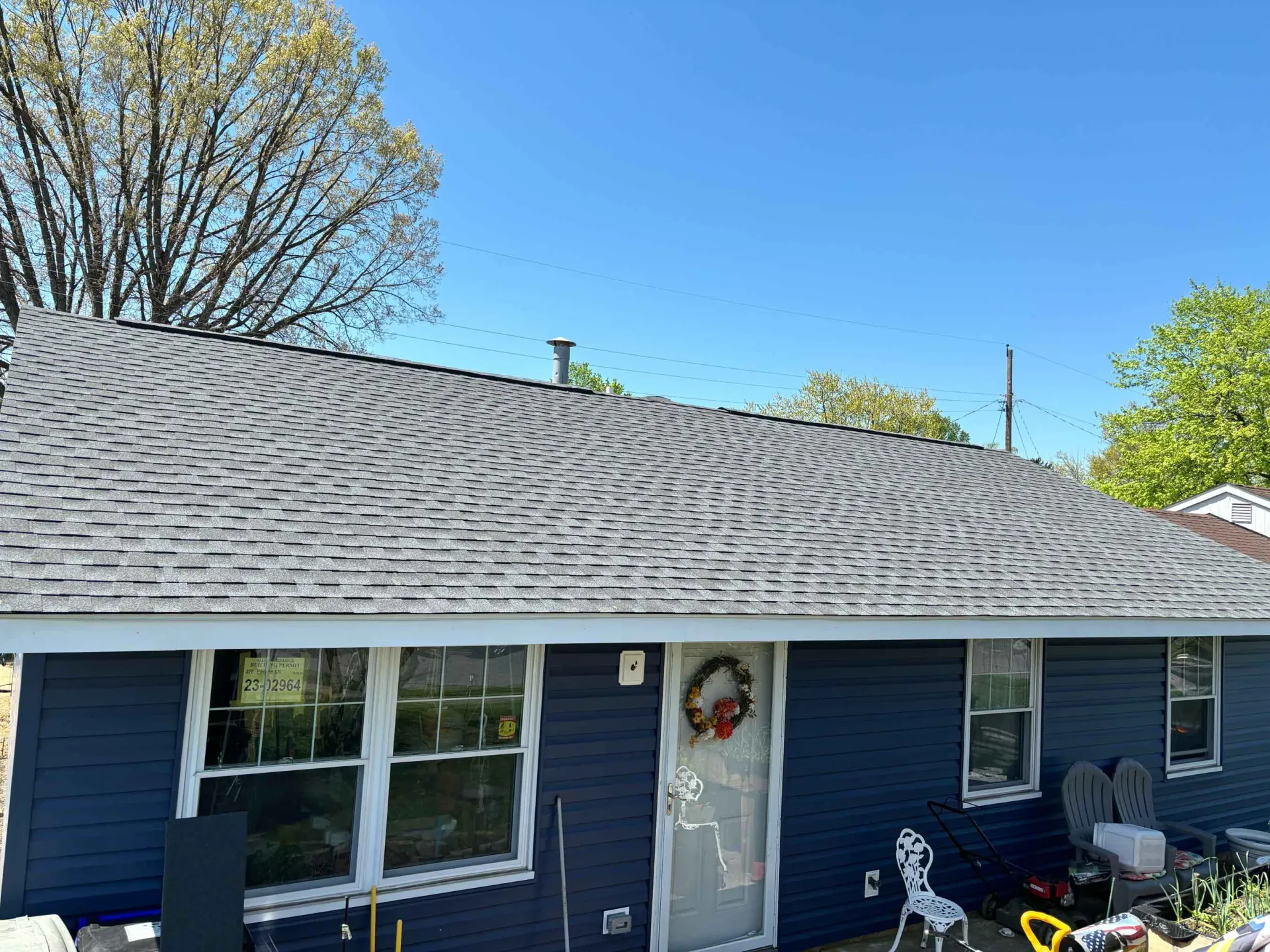 A blue house with a gray roof and a wreath on the door.
