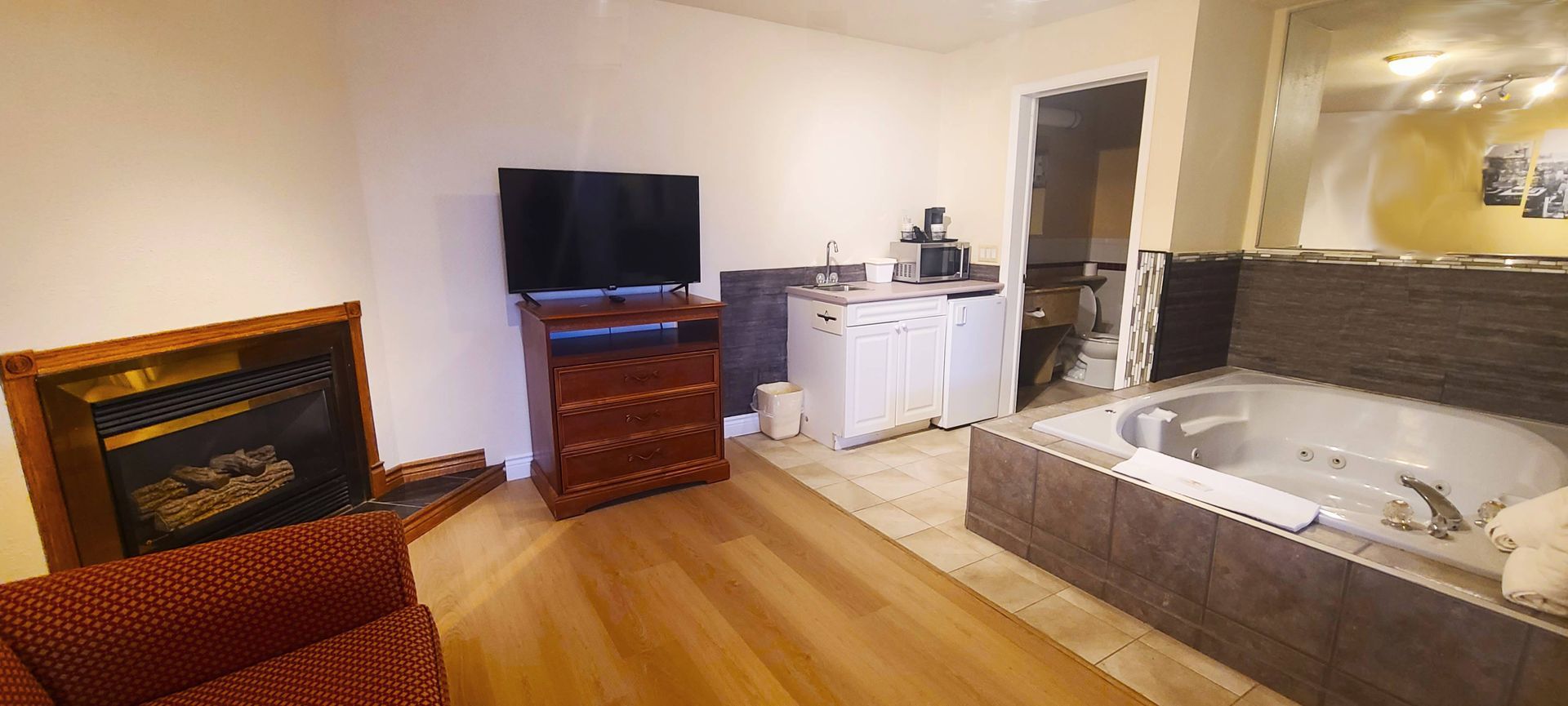 a living room with a fireplace , television , and jacuzzi tub .