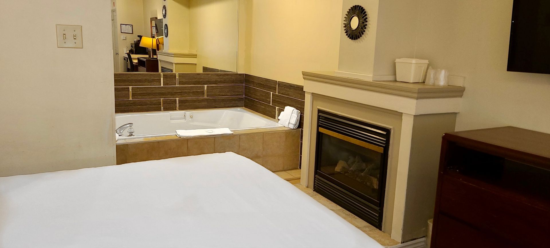 a hotel room with a bed , fireplace and jacuzzi .