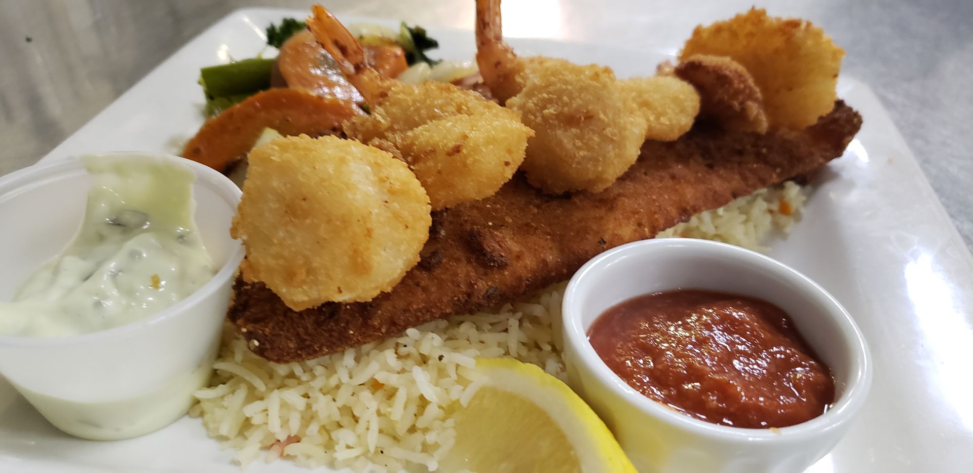 a plate of food with shrimp , rice and sauce on a table .