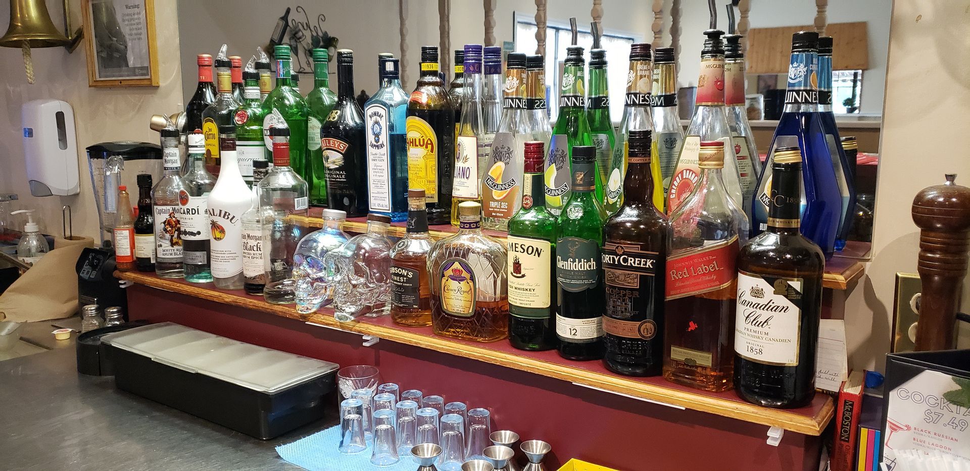 a bar filled with lots of bottles of liquor and glasses .