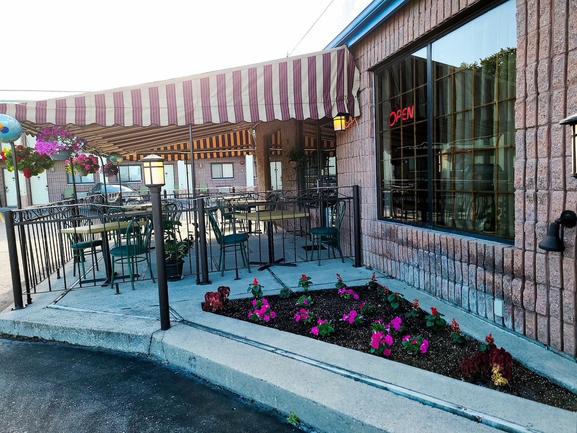 a restaurant with a patio with tables and chairs and a striped awning .