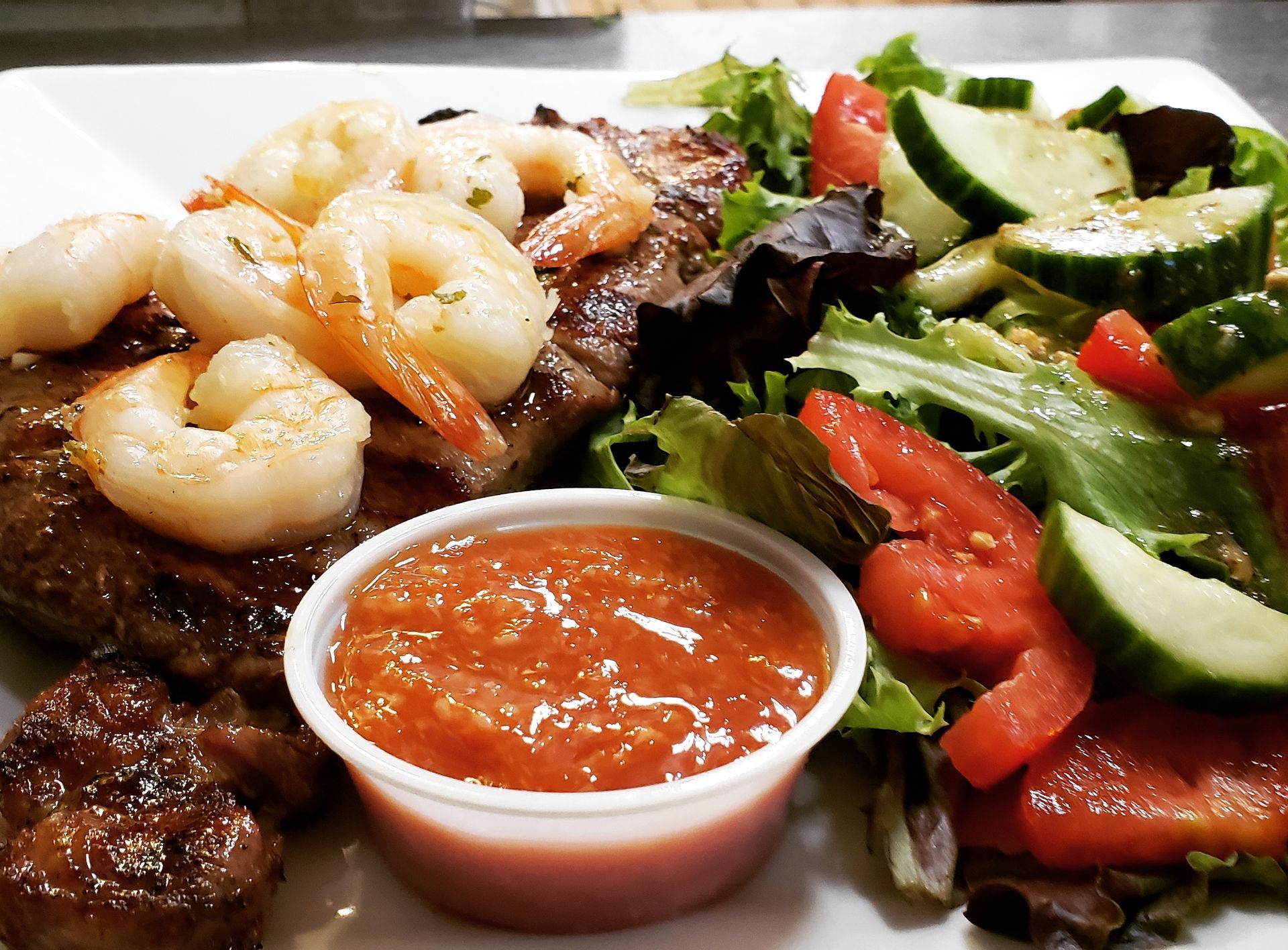 a plate of food with shrimp steak and a salad