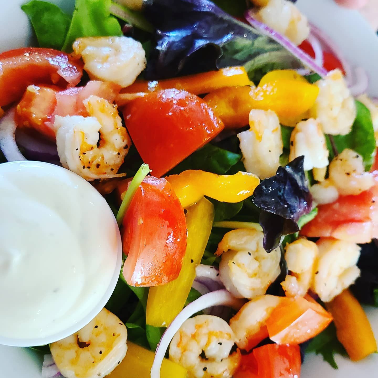 a close up of a salad with shrimp tomatoes and onions