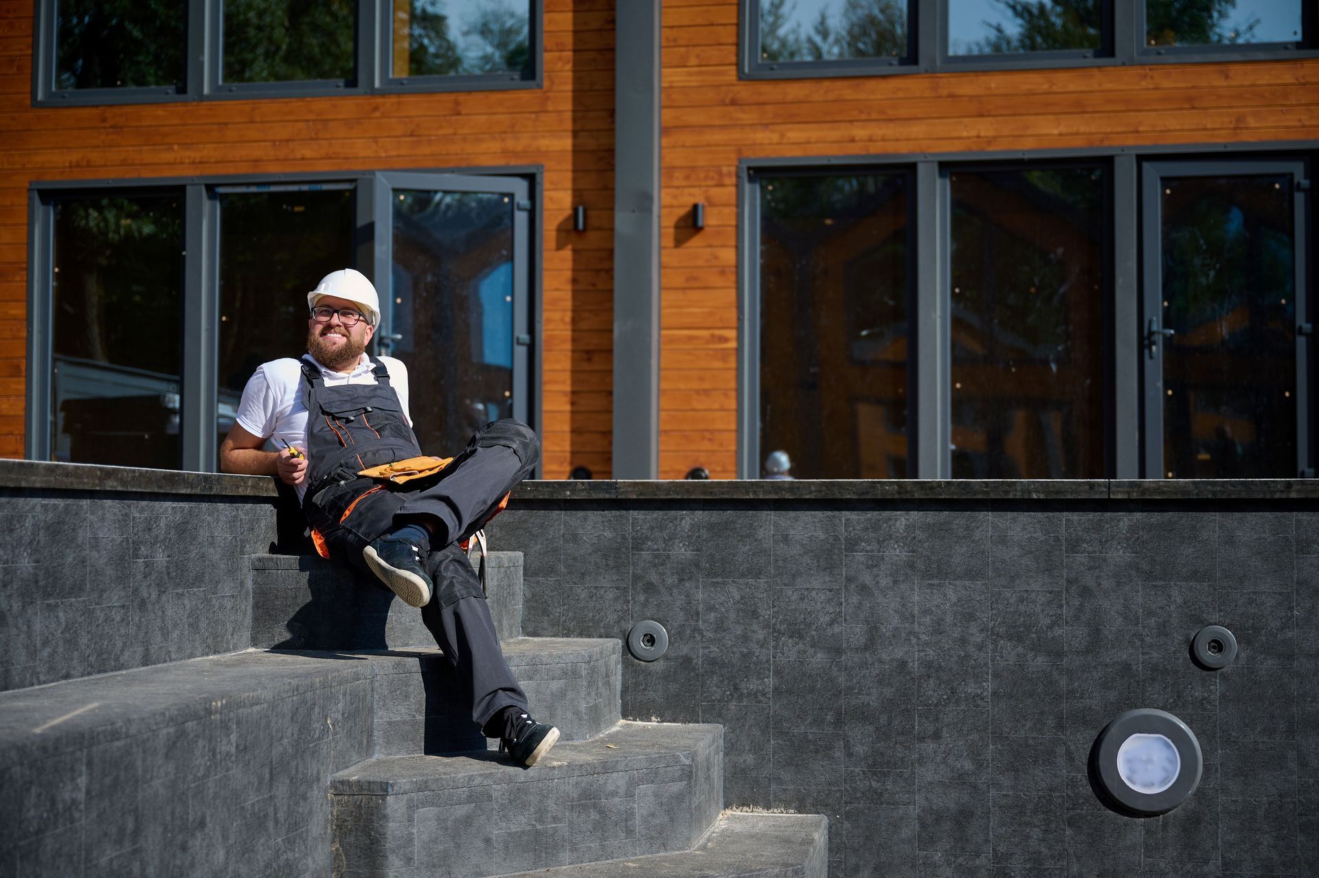 A smiling contractor sitting on the steps of an empty swimming pool. A smiling contractor sitting on the steps of an empty swimming pool.