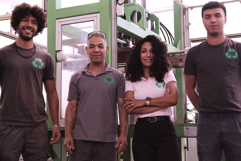 Un gruppo di persone in piedi una accanto all'altra davanti a una macchina.