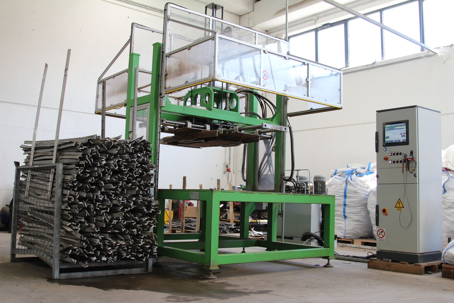 Una macchina verde è parcheggiata in un magazzino accanto a un pannello di controllo.