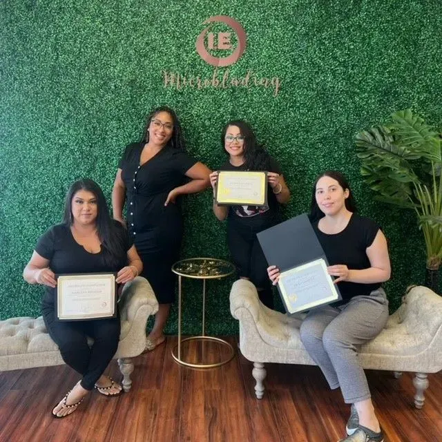 A group of women are posing for a picture in front of a wall that says le