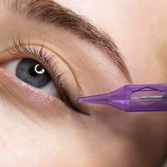 A close up of a woman getting eyeliner tattooed on her eye.