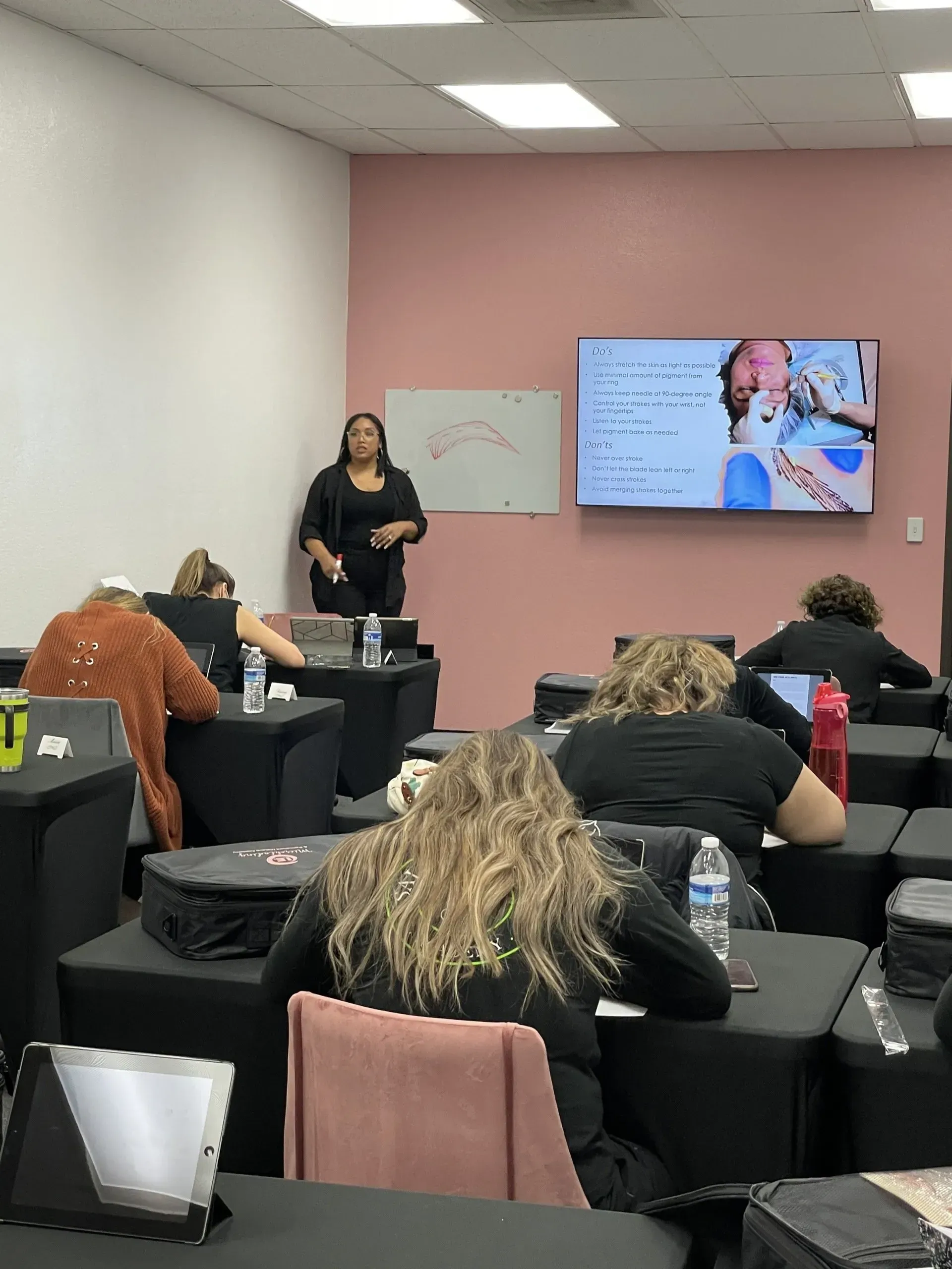 A woman is giving a presentation to a group of people in a classroom