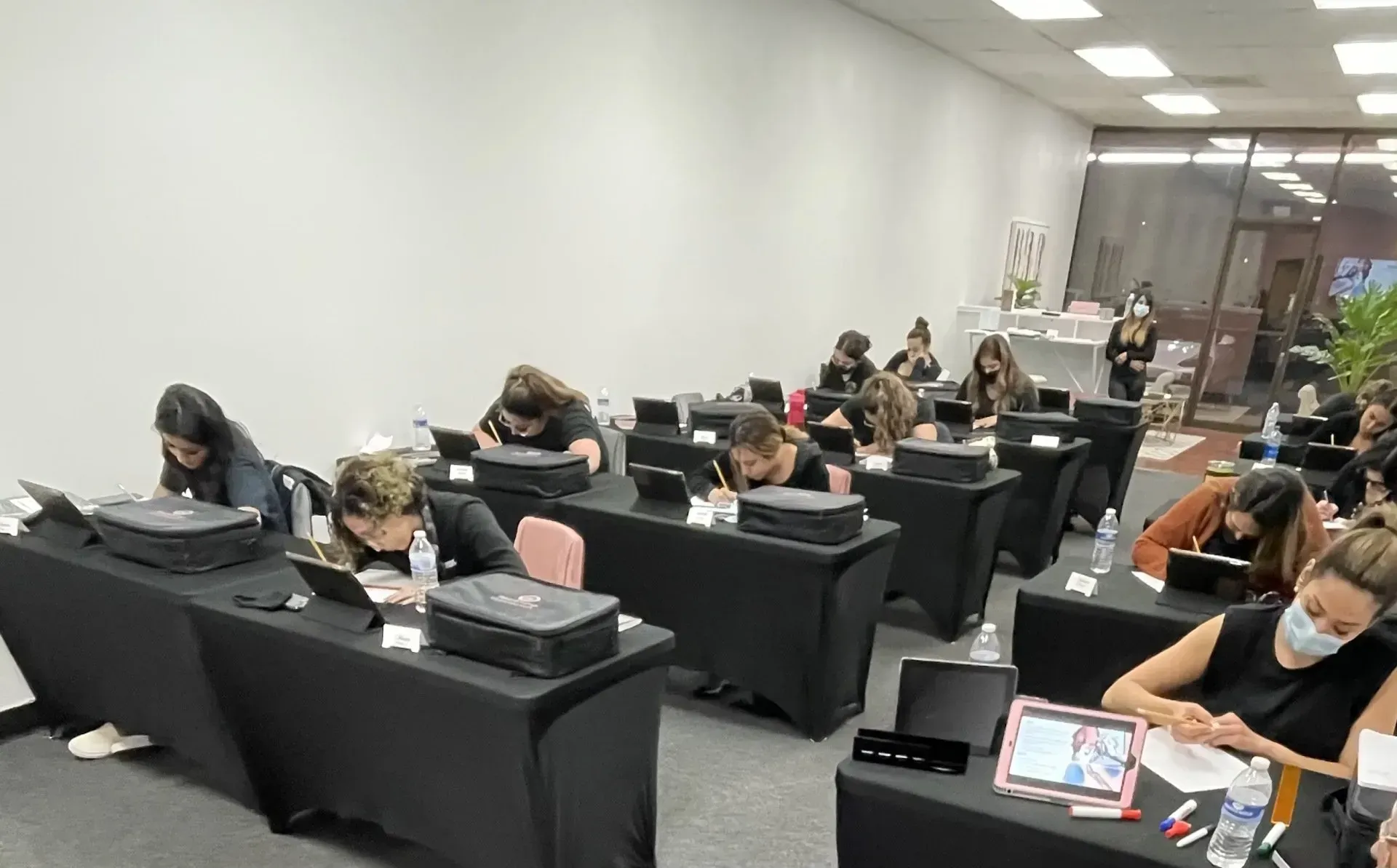 A group of people are sitting at tables in a room using laptops.
