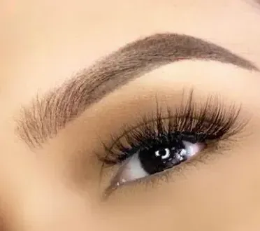 A close up of a woman 's eye with long eyelashes and a brow.