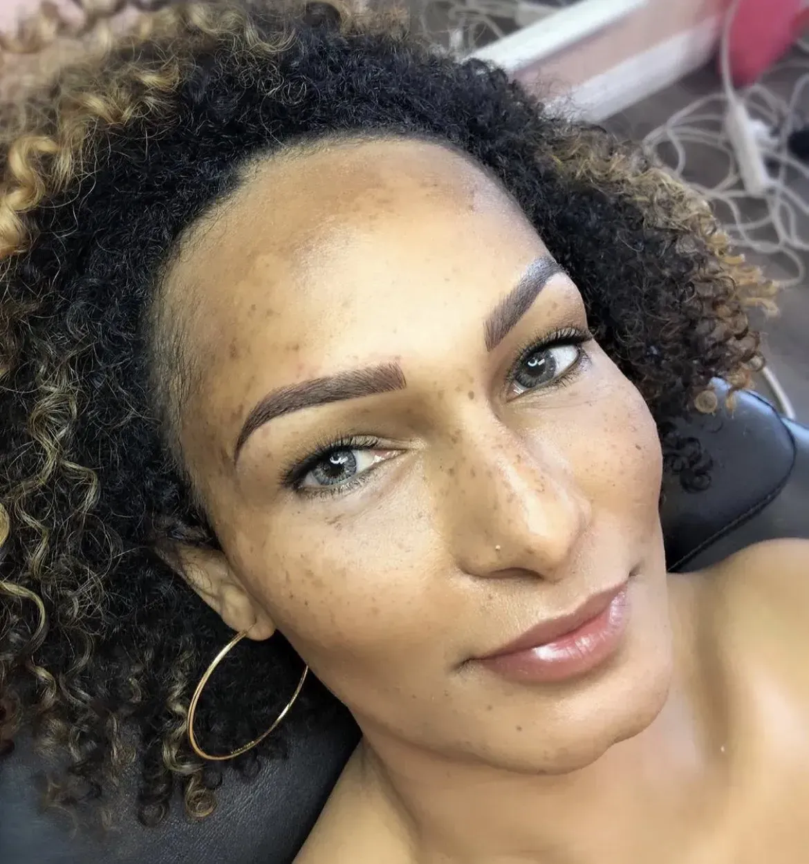 A close up of a woman 's face with curly hair and hoop earrings