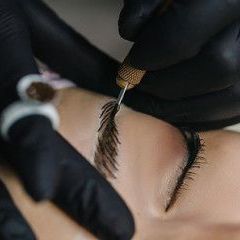 A woman is getting a permanent makeup tattoo on her eyebrows.