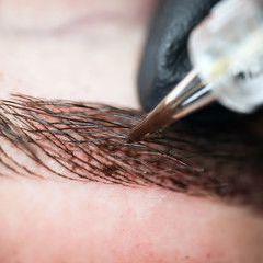 A close up of a person getting a tattoo on their eyebrows.